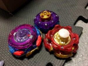 bottom view of three beyblades imperial with expand and spiral dash lord vanguard bearing and archer with around xtend plus