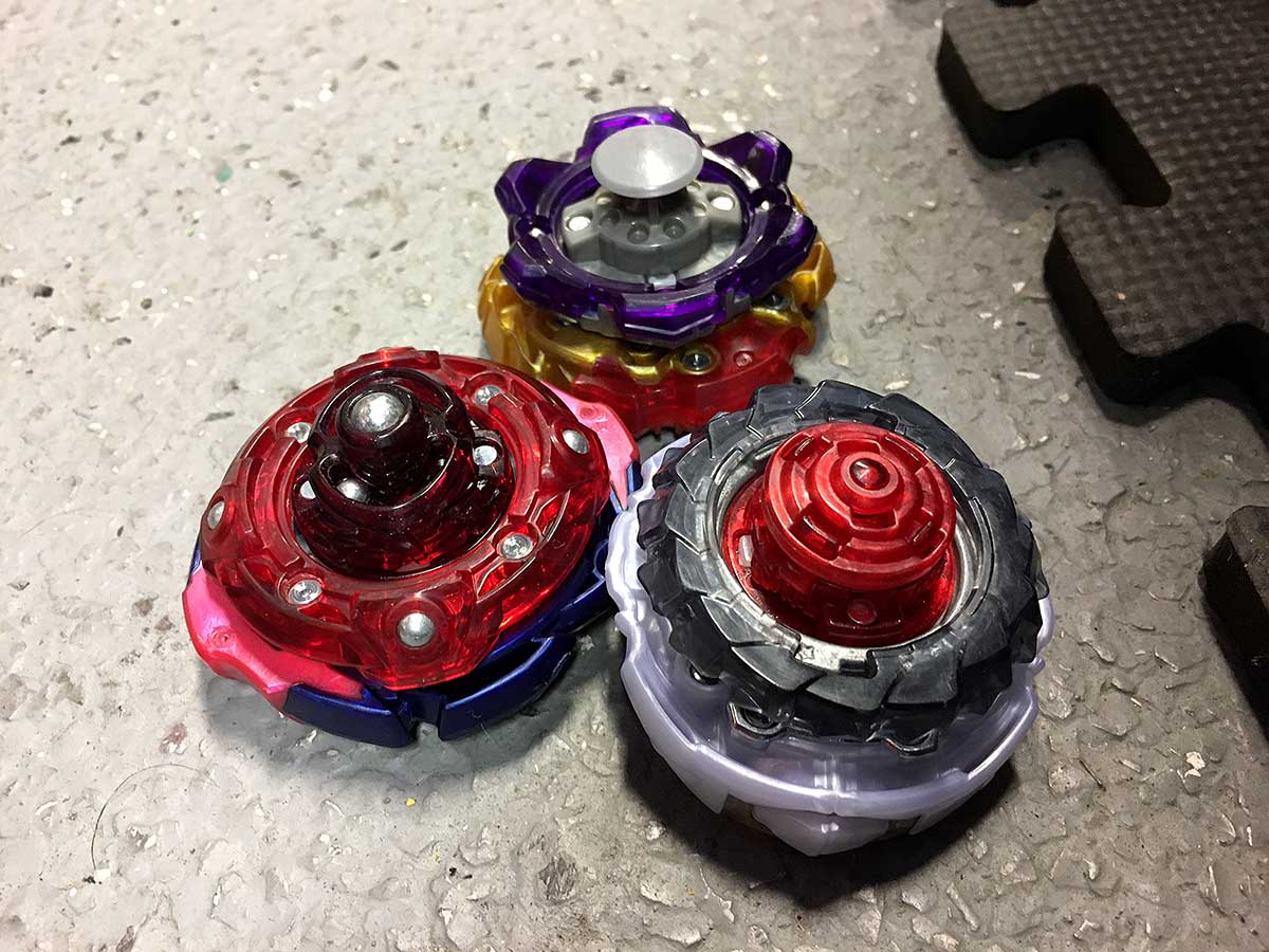 bottom view of three beyblades judgment around planet regalia genesis with bump xtend plus and lord vanguard bearing