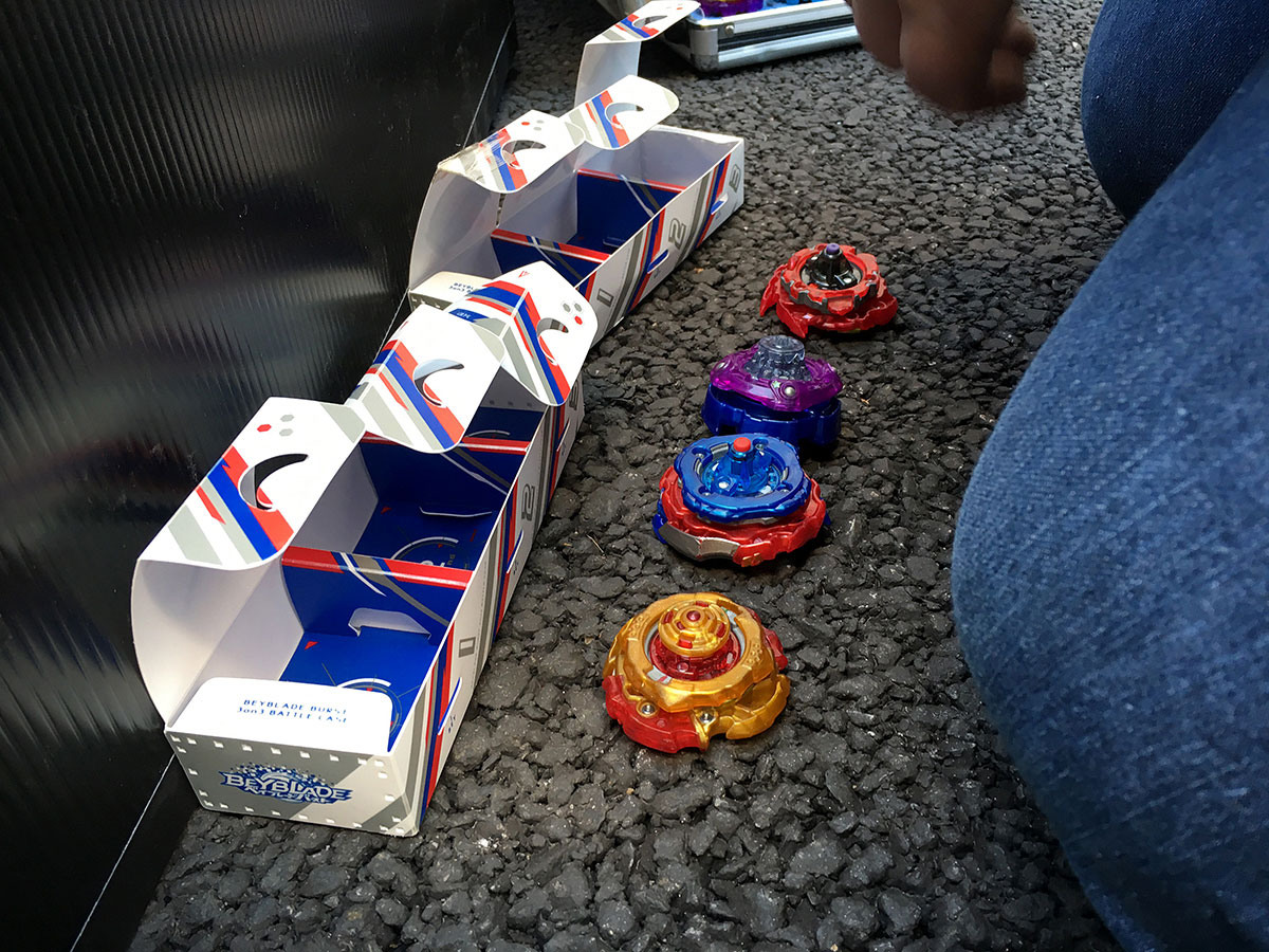 four beyblades in front of two 3on3 beyblade burst deck boxes