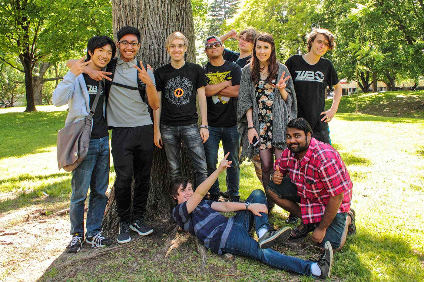 group photo of nine people in front of tree in park