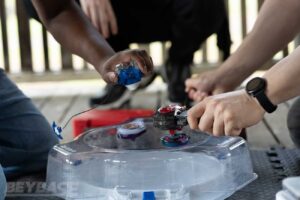 two players launching beyblades into white stadium