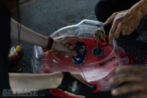 two players launching beyblades into red stadium