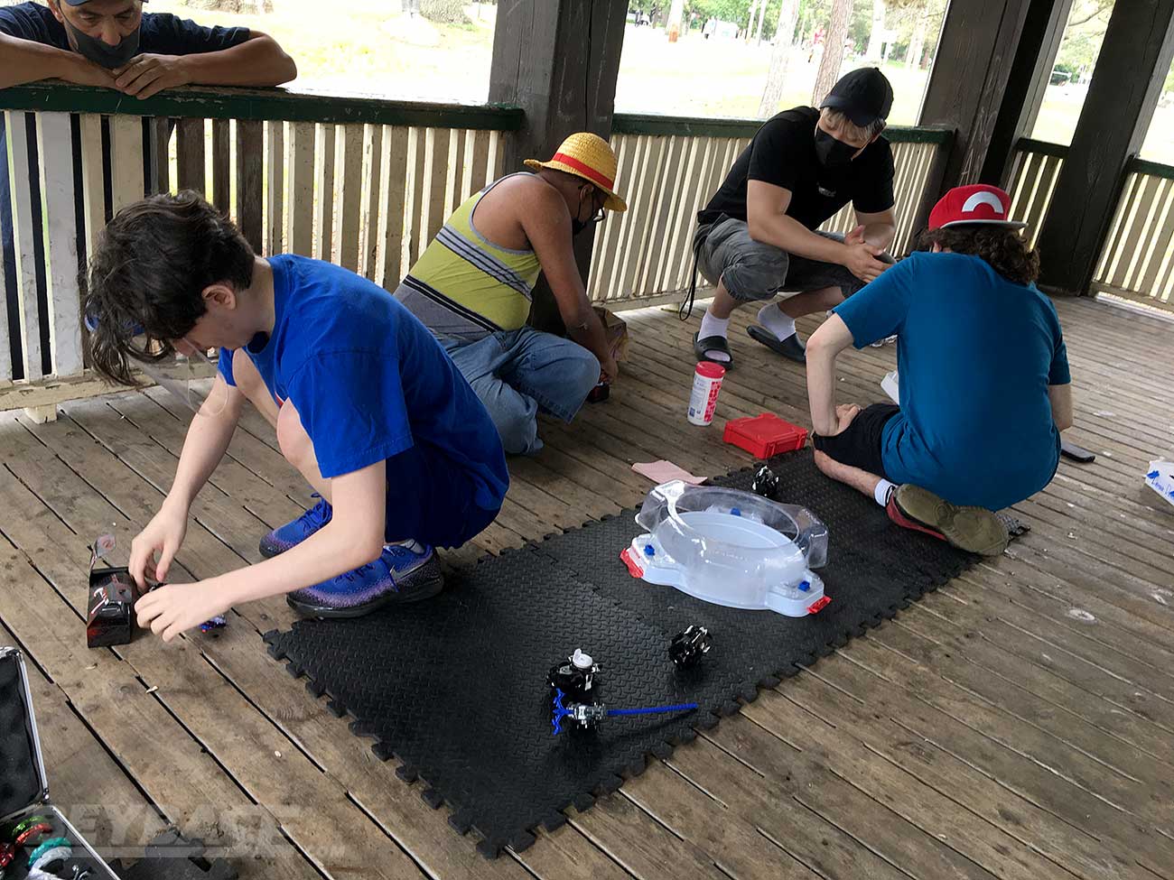 two players facing away from each other with beyblade stadium between them