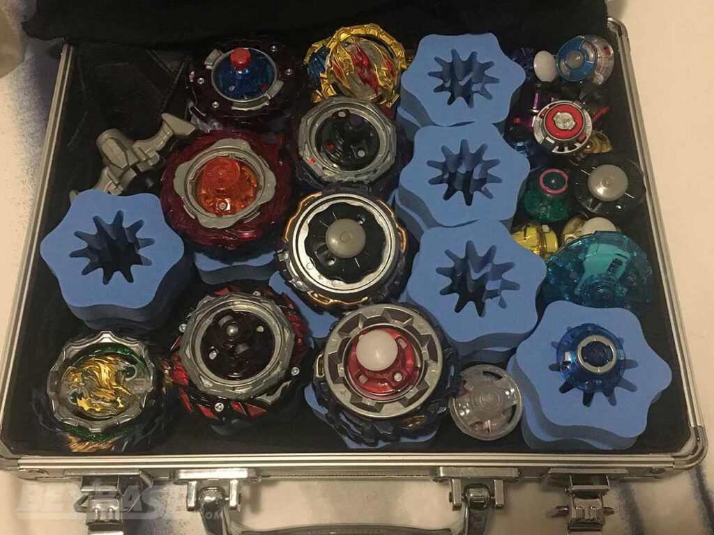beyblade attache case opened with six beyblades and many parts inside