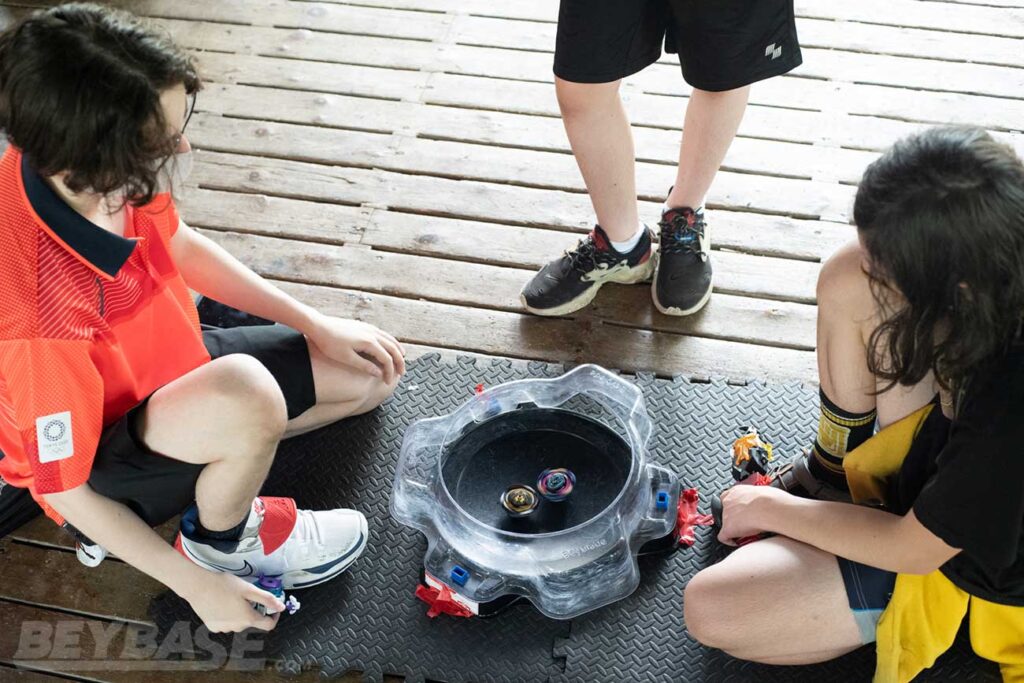 beyblade players watching beyblades inside black stadium during match