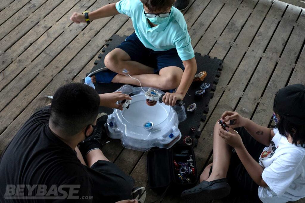 action shot of two players launching beyblades into white stadium