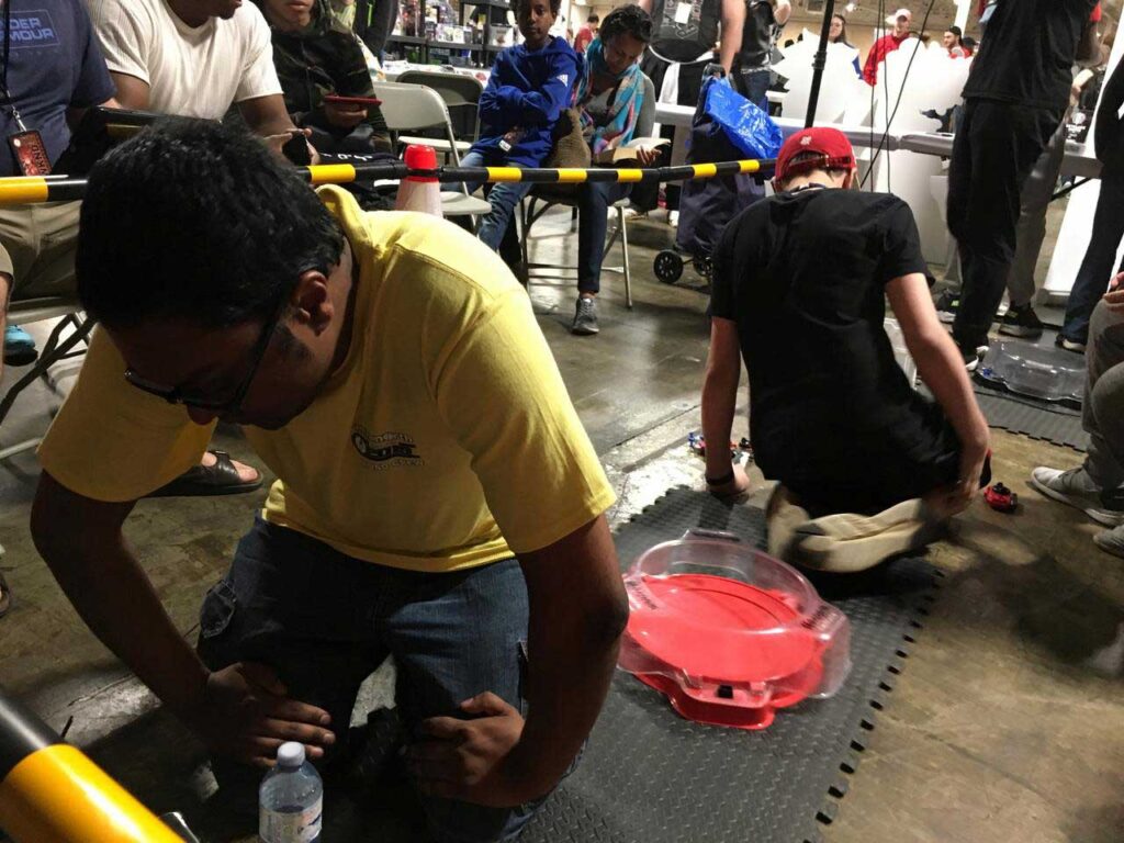 two beyblade players facing away from each other at stadium getting ready for battle