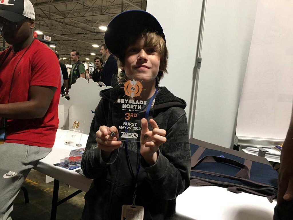boy holding clear acrylic third place beyblade north trophy