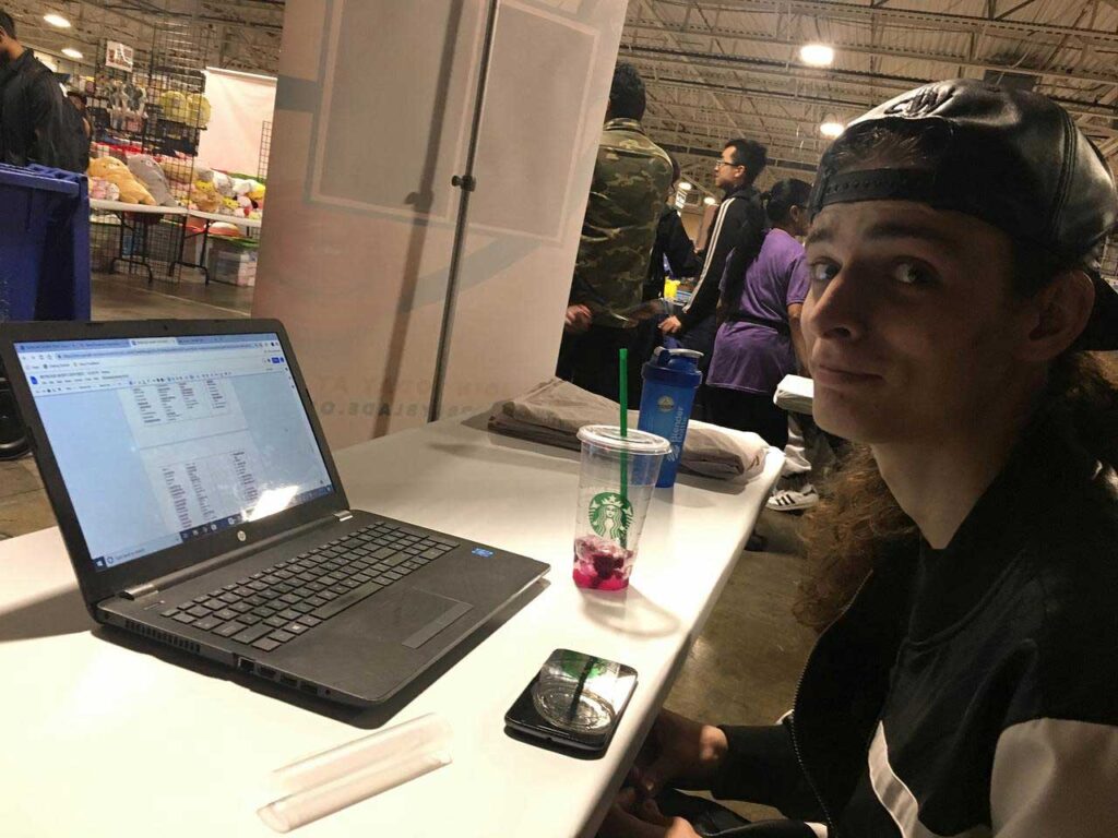 man looking at camera while sitting in front of laptop