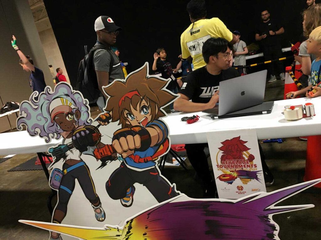 cutouts of world beyblade organization mascots taka and fumi sitting in front of table